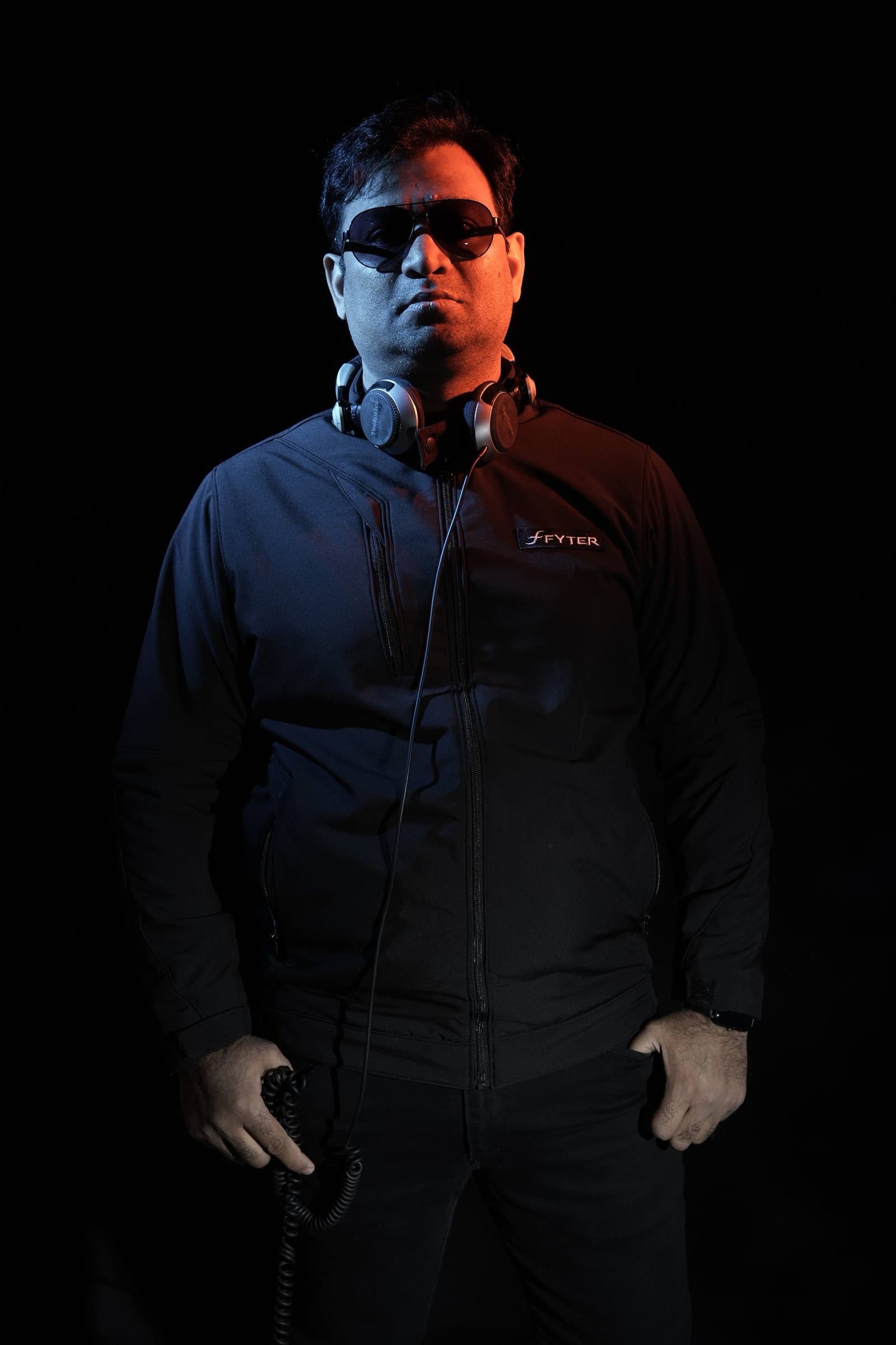 DJ Abdul standing, headphones around his neck
